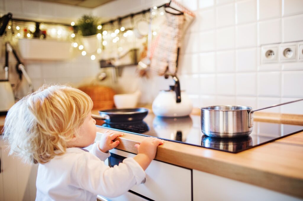 Toddler boy in dangerous situation at home. Child safety concept.